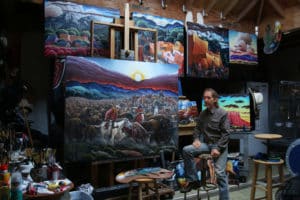 artist in studio with paintings for an art museum in Denver